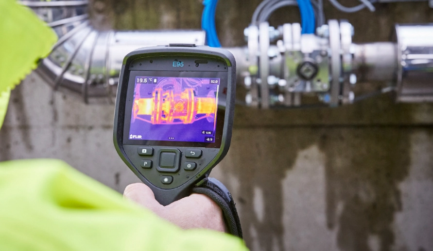 A person examining pipes with a thermal imaging camera