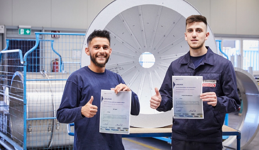 Two young men holding their German Insulation Championship certificates up to the camera