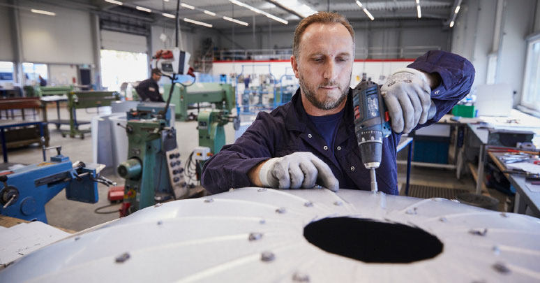 Isolierfacharbeiter arbeitet mit einem Bohrer, in einer Werkstatt, an einer Isolierung