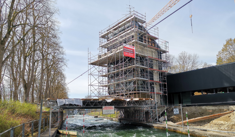 A river with a bridge and neighbouring building covered in scaffolding.